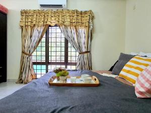 a tray of food on a bed with a window at Melaka Afamosa Villa with Private Pool for 10 pax in Kampong Alor Gajah