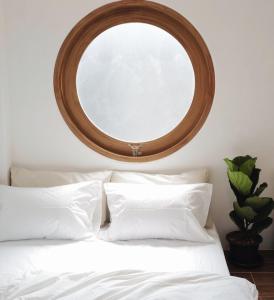 um espelho redondo por cima de uma cama com almofadas brancas em Marlowe-Tony's home em Bangkok