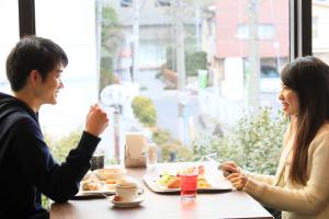 a man and woman sitting at a table eating food at Richmond Hotel Yokohama Ekimae in Yokohama