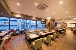 a restaurant with tables and chairs and windows at Richmond Hotel Yokohama Ekimae in Yokohama