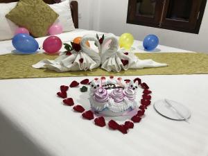 a heart shaped cake on a bed with balloons at Elephant Boutique Hotel in Luang Prabang