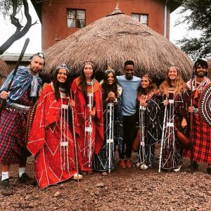 Un gruppo di persone che si trovano davanti a una capanna di Maasai Hostel Tanzania ad Arusha