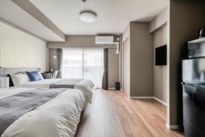 two beds in a hotel room with a television at BON Condominium Namba Ebisu in Osaka