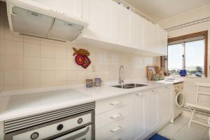 una cocina con armarios blancos y fregadero en Barra Beach House - Praia da Barra, en Praia da Barra