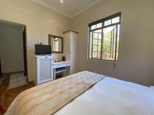 a bedroom with a bed and a desk and a window at Turnberry Boutique Hotel in Oudtshoorn