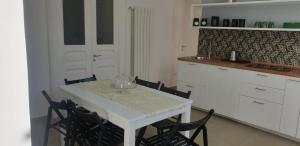 una cocina con una mesa blanca con sillas y una barra en MaGà Station, en Nápoles