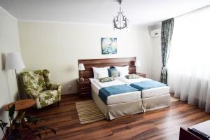 a bedroom with a bed and a chair and a chandelier at Cabrio Apart Hotel in Cluj-Napoca