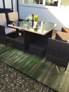 une table et des chaises sur une terrasse avec un plateau en verre dans l'établissement Beach Links, à Prestatyn