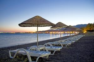 una fila de sillas y sombrillas en una playa en Adrina Termal Health & SPA Hotel, en Gure
