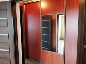 a closet with wooden doors and a mirror at Апартаменты в самом центре Витебска in Vitebsk