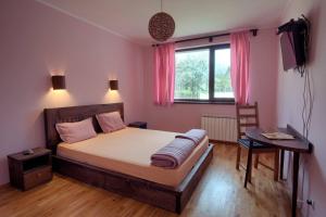 a bedroom with a bed and a table and a window at Guest House Villa Bozhenitsa in Bozhenitsa