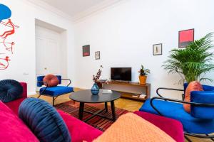 een woonkamer met blauwe en rode meubels en een televisie bij ❂Light and Luxurious 2BR Home + Balcony in the City Center❂ in Tbilisi City