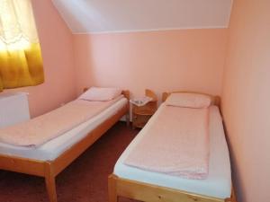 2 camas en una habitación pequeña con ventana en Hajnal vendégház, en Căpîlniţa