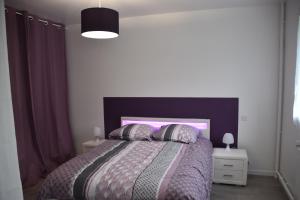Schlafzimmer mit einem Bett mit einem lila Kopfteil und Kissen in der Unterkunft G.Y.T.E'S in Honfleur