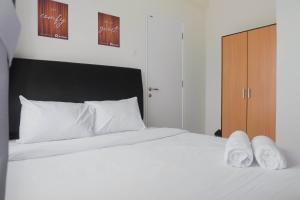 a white bed with white pillows and a wooden cabinet at Exclusive 2BR Bogorienze Resort Bogor near The Jungle By Travelio in Bogor