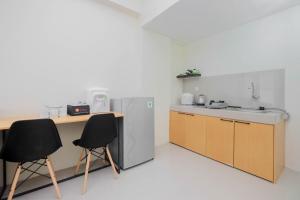 a kitchen with a refrigerator and a table and two chairs at Exclusive 2BR Bogorienze Resort Bogor near The Jungle By Travelio in Bogor