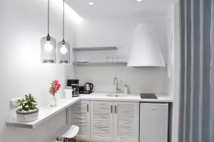 a white kitchen with white cabinets and a sink at Crystal Mare Suites in Naxos Chora