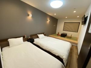 two beds in a room with a tv on the wall at KYOTO STATION HOUSE in Kyoto