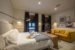 1 dormitorio con cama, sofá y TV en Barbarossa Suites Plaza de España en Merida