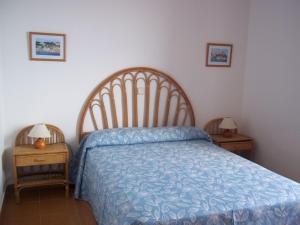 una camera da letto con un letto con un piumone blu e due tavoli di Apartamentos Rocas Marinas a Punta Grossa