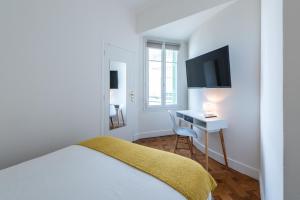 a bedroom with a bed and a desk with a television at La Suite 111 in Nice