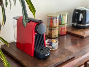 a red and black toaster sitting on a wooden table at Kauri Glen BnB in Te Arai