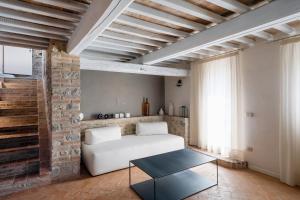 Monteleone dʼOrvietoにあるBorgo Giorgioneの白いソファとレンガの壁が備わるリビングルーム