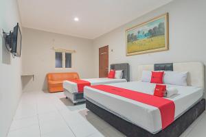 RedDoorz Plus at Bukit Cinta Street Balikpapan في Klandasan Kecil: غرفة نوم بسريرين وكرسي برتقال
