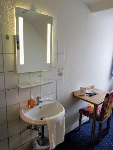 ein Bad mit einem Waschbecken und einem Spiegel in der Unterkunft Hotel Flora in Hannover