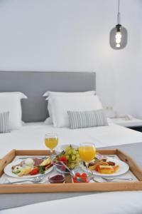 una bandeja de comida y dos copas de vino en una cama en Crystal Mare Suites, en Naxos Chora