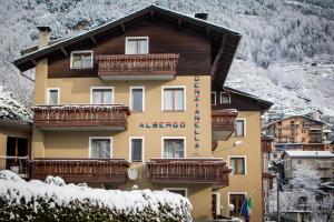 a large building with balconies and snow on the ground at Hotel Genzianella in Chiesa in Valmalenco