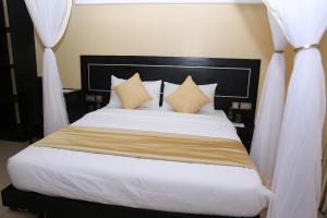 1 dormitorio con 1 cama grande con sábanas y almohadas blancas en Anchor Hotel, en Nairobi