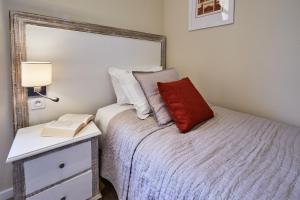 a bedroom with a bed with a red pillow and a nightstand at Les Villas d'Arromanches, Teritoria in Arromanches-les-Bains