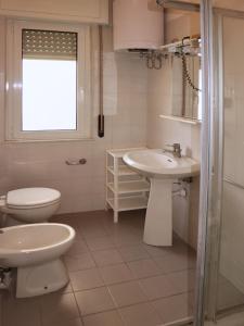 bagno bianco con servizi igienici e lavandino di Stiria a Lignano Sabbiadoro