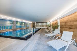 a swimming pool with white chairs in a house at Kertess in Sankt Anton am Arlberg