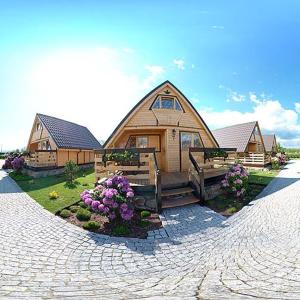 a large wooden house with flowers in front of it at Gościniec Nad Bukówką in Lubawka