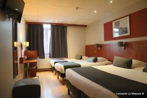 een hotelkamer met 4 bedden en een televisie bij Hôtel de l'Univers Liège in Luik
