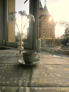 a coffee cup sitting on a table in front of a window at Ultracentral Cathedral Apartament Timisoara in Timişoara