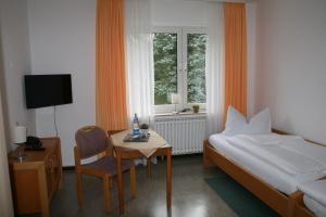 ein Schlafzimmer mit einem Bett und einem Tisch mit einem Stuhl in der Unterkunft Gästehaus Bleibergquelle in Velbert
