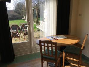 einen Tisch und Stühle in einem Zimmer mit Fenster in der Unterkunft Carels Kamers Texel in De Koog