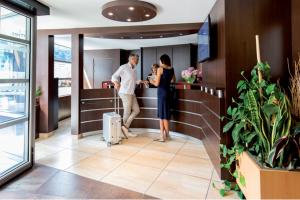 a man and a woman standing at a counter at Hotel Thermes Les Ecureuils-Dax in Dax