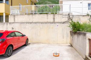a red car parked in a parking lot at Ana Apartment in Cavtat