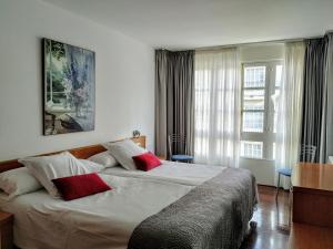 sypialnia z dużym łóżkiem z 2 czerwonymi poduszkami w obiekcie Hotel Hórreo by Bossh! Hotels w Santiago de Compostela