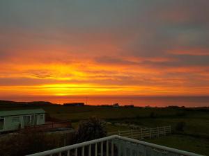 a sunset over the ocean with a house and a fence at Sunrise view in Ballina