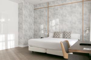 a bedroom with a large white bed and a desk at Teatro Romano 7 & 8 in Málaga