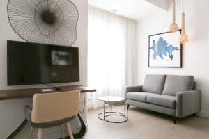 a living room with a tv and a couch and a chair at Teatro Romano 7 & 8 in Málaga