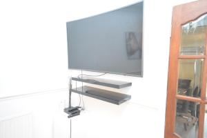 a flat screen tv hanging on a wall at London Luxury 5 Bedroom House 2 min walk to the Tube Station in Dagenham