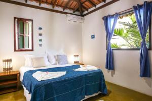 a bedroom with a bed with blue sheets and a window at Vila Som do Mar in Trancoso