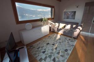 - un salon avec un canapé et une grande fenêtre dans l'établissement Magic lake view with beautiful pool area (camelia), à Bellano