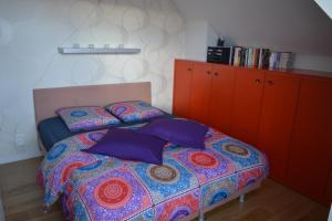 a bedroom with a bed with purple pillows and orange cabinets at Maison Anna Clara in Nieuwpoort